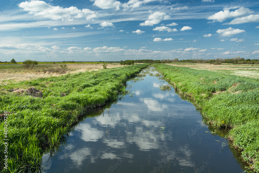 Reflection of white clouds in a calm and small river Reflection of white clouds in a calm and small river
