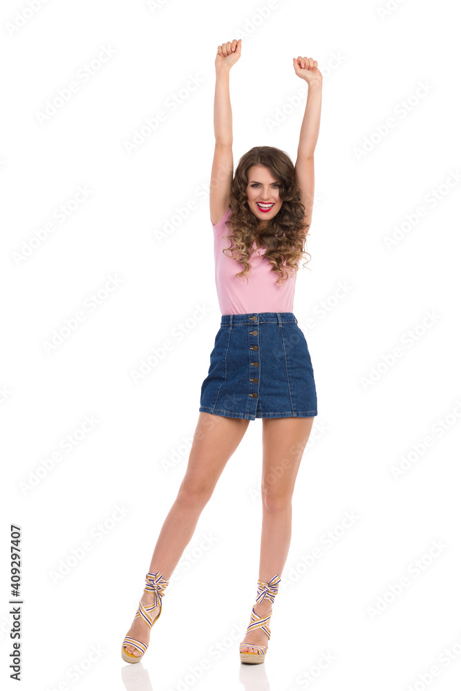 Happy Woman In Jeans Mini Skirt And Wedge Shoes Is Standing With Arms Raised And Cheering