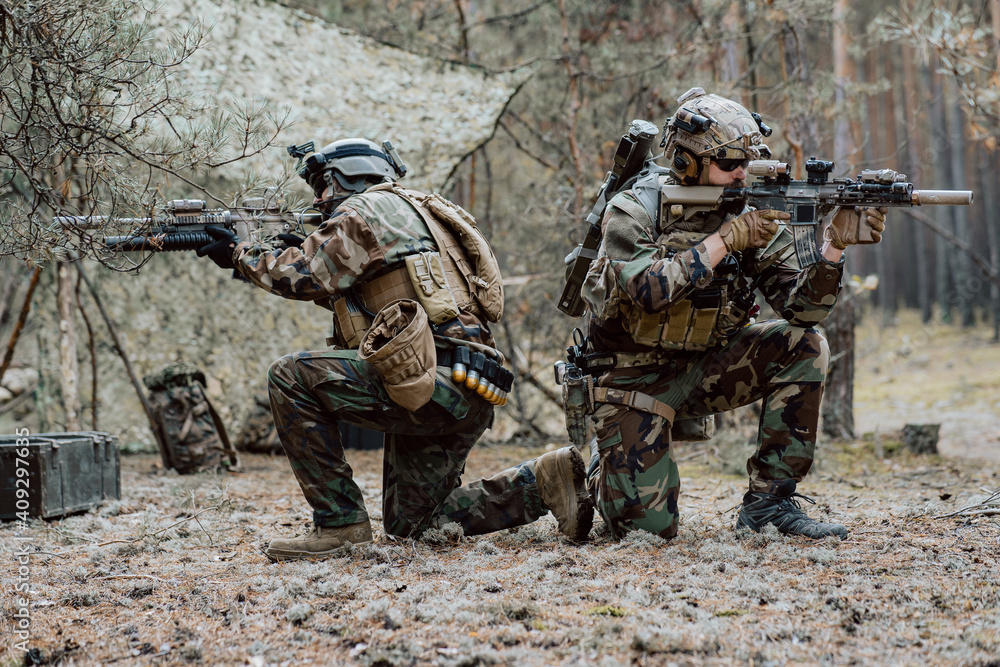 Fototapeta premium Squad of Four Fully Equipped Soldiers in Camouflage on a Reconnaissance Military Mission, Aiming Rifles. They're Moving in Formation Through Dense Pine Forest.