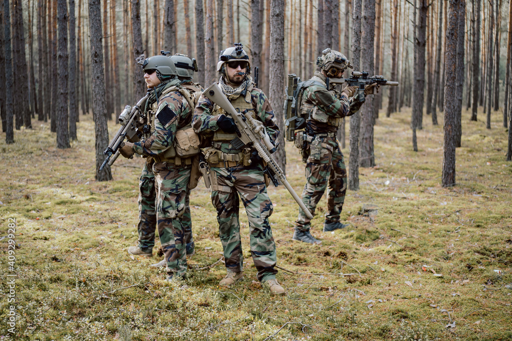 Portrait of a middle-aged bearded soldiers in a Woodland military uniform and helmet, with headphones on his head holding a rifle. Portrait of a middle-aged bearded soldiers in a Woodland military uniform and helmet, with headphones on his head holding a rifle.