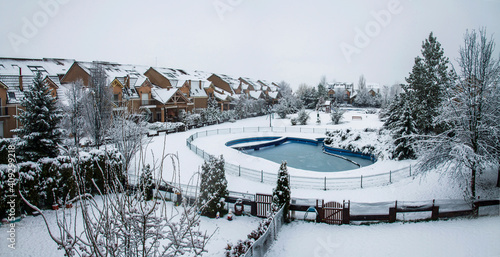 Snow covered yard with a pool in a beautiful neighborhood in Bucharest. Christmas background. Cold temperature, winter time © andrijosef