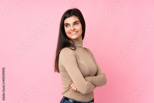 Young woman over isolated pink background with arms crossed and happy