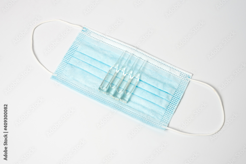 Injection syringe and vaccine on a medical mask. Injection syringe and vaccine on a medical mask.