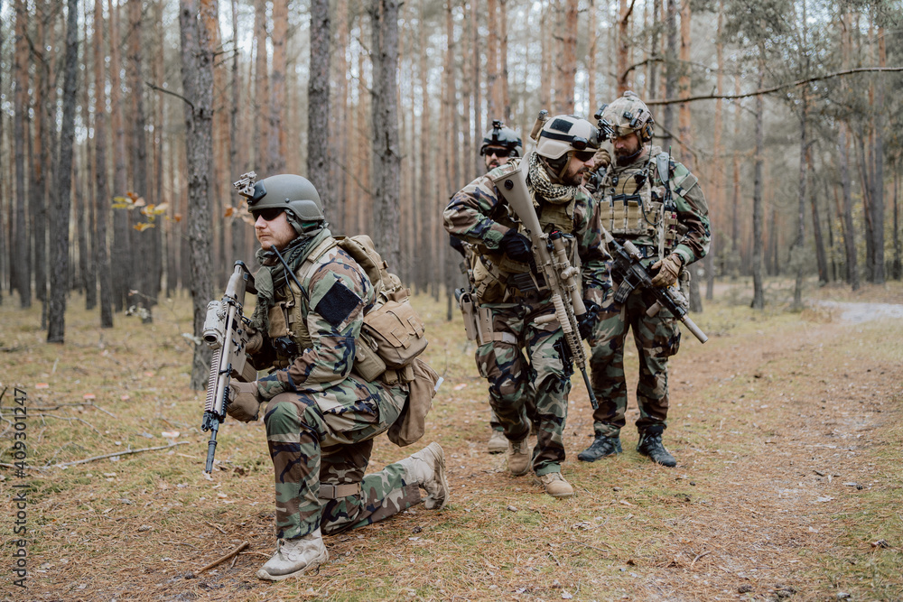 Portrait of a middle-aged bearded soldiers in a Woodland military uniform and helmet, with headphones on his head holding a rifle. Portrait of a middle-aged bearded soldiers in a Woodland military uniform and helmet, with headphones on his head holding a rifle.