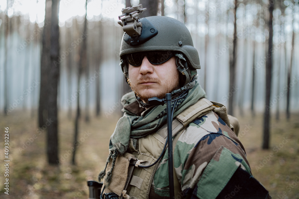 Portrait of a middle-aged bearded soldier in a Woodland military uniform and helmet, with headphones on his head. Portrait of a middle-aged bearded soldier in a Woodland military uniform and helmet, with headphones on his head.