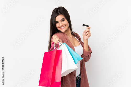 Young woman over isolated white background holding shopping bags and a credit card