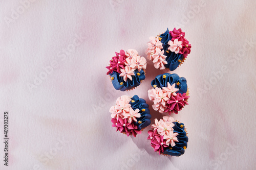Fototapeta Naklejka Na Ścianę i Meble -  Blue and Pink Floral Cupcakes on Pink Background with Space for Copy