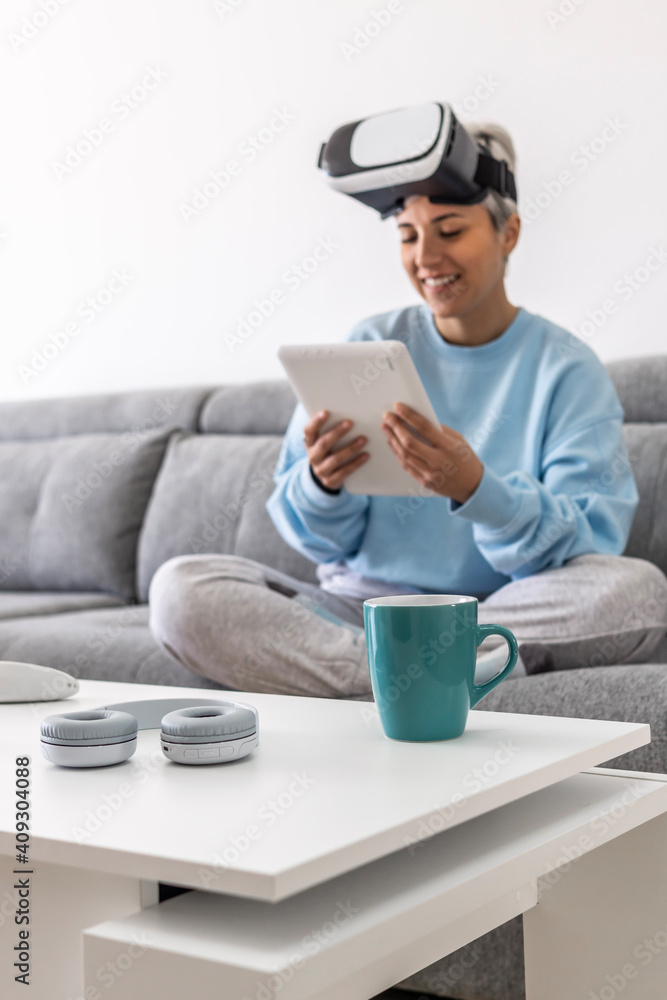 Beautiful girl on the couch at home wearing virtual reality glasses and browsing the internet with a tablet Beautiful girl on the couch at home wearing virtual reality glasses and browsing the internet with a tablet