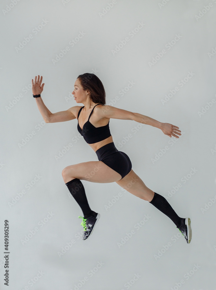A woman in a sporty image jumps on a white background