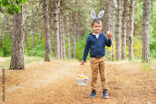 A child looking for Easter eggs in the forest. Little boy hunting for Easter egg in spring wood on Easter day. The concept of Easter Egg Hunt