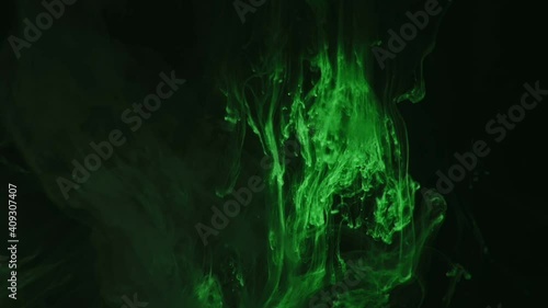 Green paint drops mixing in water slow motion. Smooth ink swirling and splashing from above underwater. Ink cloud on black background. Colored abstract smoke explosion.