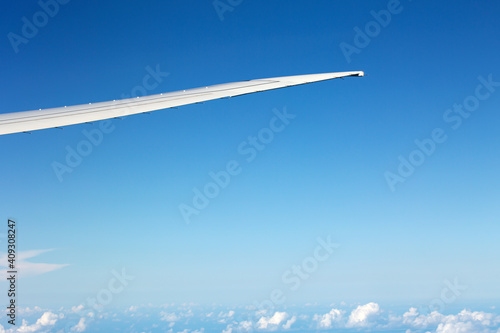 Window view on airplane wing with sky and clouds background