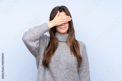 Teenager Brazilian girl over isolated blue background covering eyes by hands. Do not want to see something