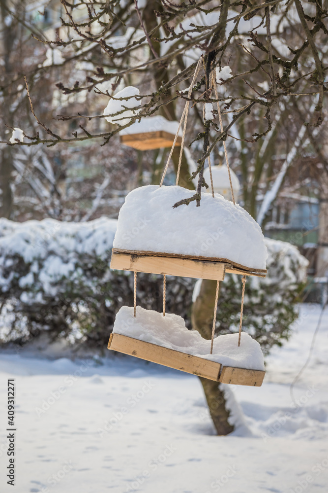The bird feeder is covered with snow near the school. Wooden bird table topped with fresh snow The bird feeder is covered with snow near the school. Wooden bird table topped with fresh snow