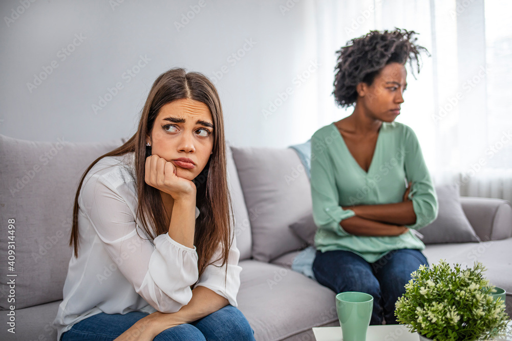 Unhappy friends not talking after argument on the couch. Two upset friends not talking to each other after fight on the sofa in sitting room at home. Unhappy friends not talking after argument Unhappy friends not talking after argument on the couch. Two upset friends not talking to each other after fight on the sofa in sitting room at home. Unhappy friends not talking after argument