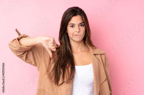 Teenager Brazilian girl over isolated pink background showing thumb down sign