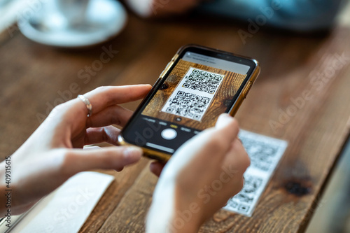 Young woman hands using the smart phone to scan the qr code to select food menu in the restaurant. photo