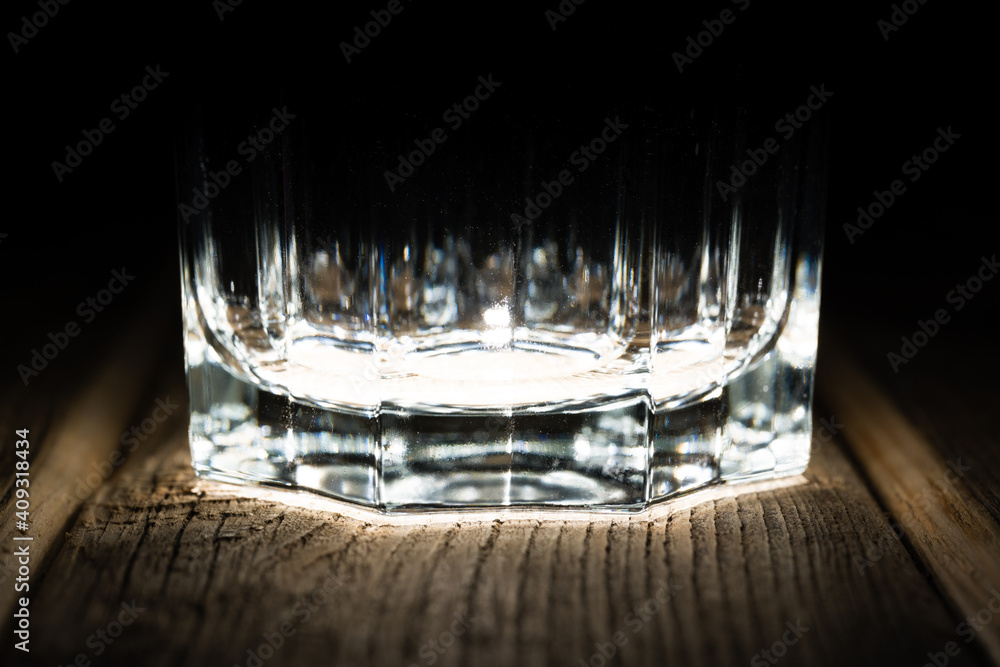 the bottom of the glass on a wooden table, under the spotlight
