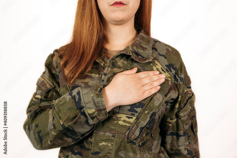 Woman in military camouflage standinwith her hand on her heart Woman in military camouflage standinwith her hand on her heart