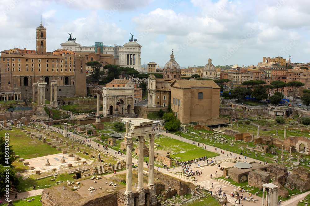 Scenic view of the ruins of the Roman Forum in Rome, Italy. Dozens of tourists visiting Roman Forum. Panoramic cityscape view of the Roman Forum and world famous landmarks in Italy.