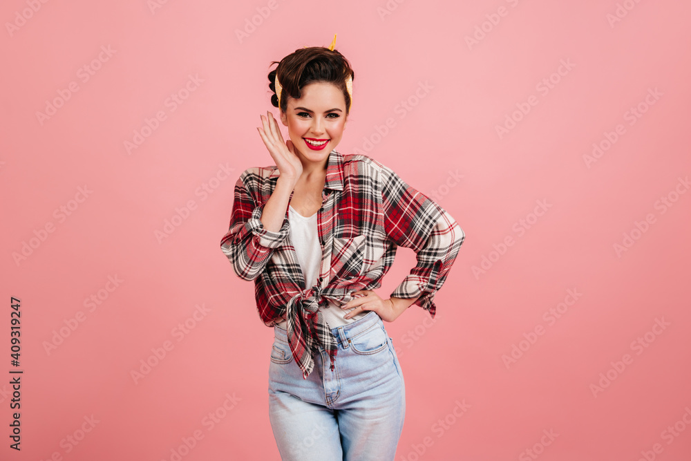 Shapely smiling pinup girl posing on pink background. Front view of playful european lady in checkered shirt. Shapely smiling pinup girl posing on pink background. Front view of playful european lady in checkered shirt.