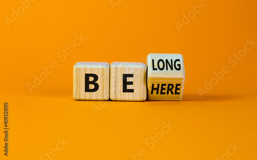 Be here belong symbol. Turned a cube and changed words 'be here' to 'belong'. Beautiful orange background. Business, belonging and be here belong concept. Copy space.