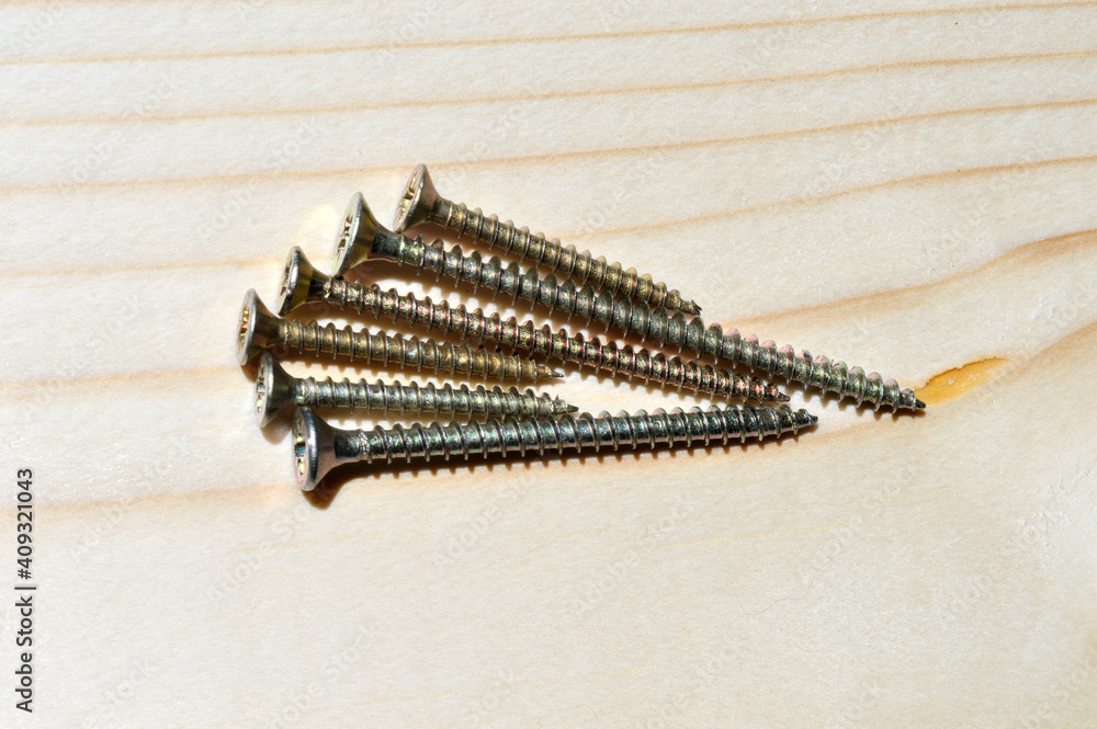 several yellow self-tapping screws on a wooden background. close-up. several yellow self-tapping screws on a wooden background. close-up.