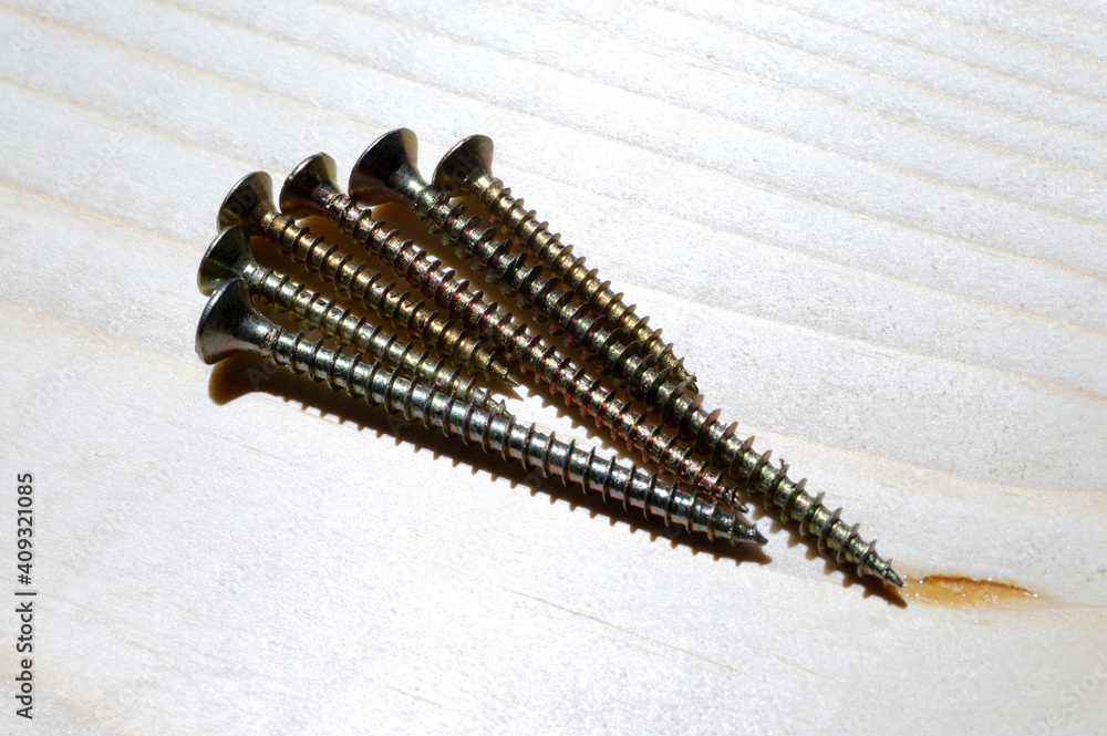 several yellow self-tapping screws on a wooden background. close-up. several yellow self-tapping screws on a wooden background. close-up.