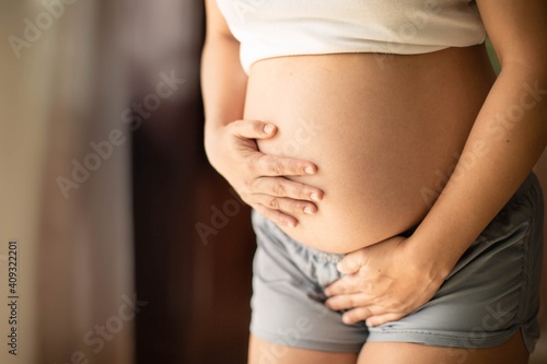 Pregnant woman holding her belly needing to pee with a week bladder. Constipation and bladder prenatal. photo