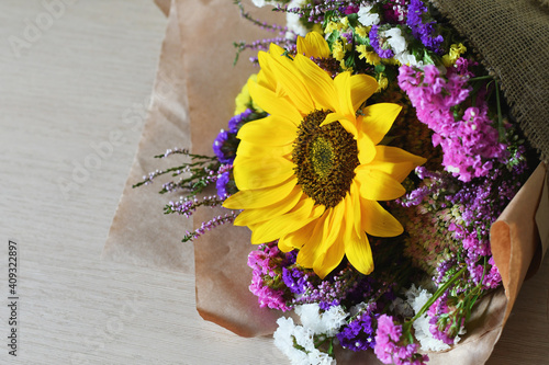 Rustic bouquet with sunflower, and yellow and violet wildflowers isolated on white background. photo