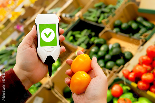 device in hand measuring nitrates and pesticides on market vegetables and fruits photo