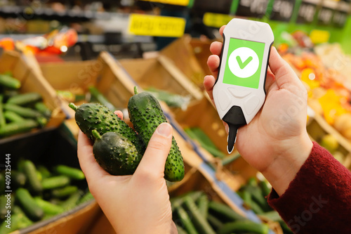 device in hand measuring nitrates and pesticides on market vegetables and fruits