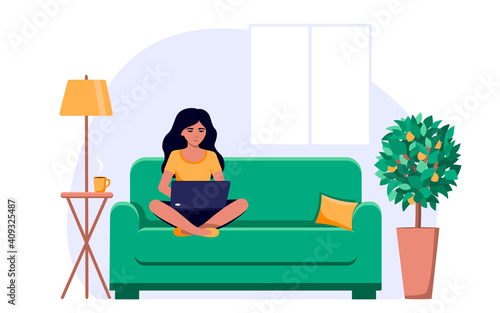 A girl is sitting on the sofa with a laptop on her lap, working or studying via the Internet .