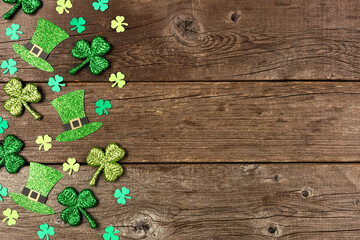 St Patricks Day shamrock and leprechaun hat side border. Above view over a rustic wood background with copy space.