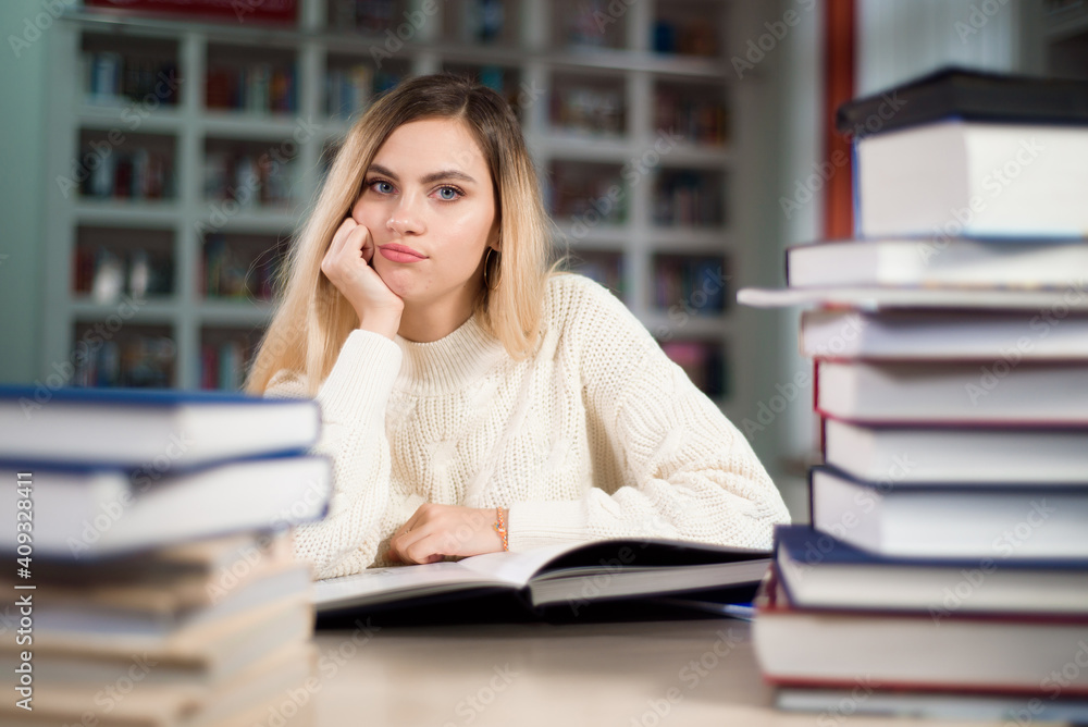 A tired student is studying in the school library. A tired student is studying in the school library.