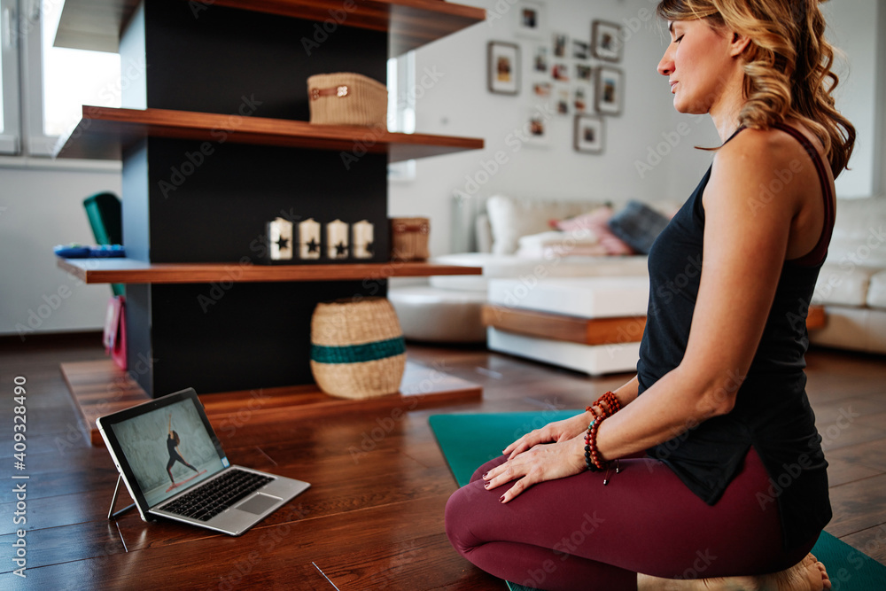 Woman practicing yoga at home with video tutorial. Woman practicing yoga at home with video tutorial.