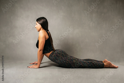 Young attractive girl doing yoga, lying in Cobra pose. Studio photo shoot.