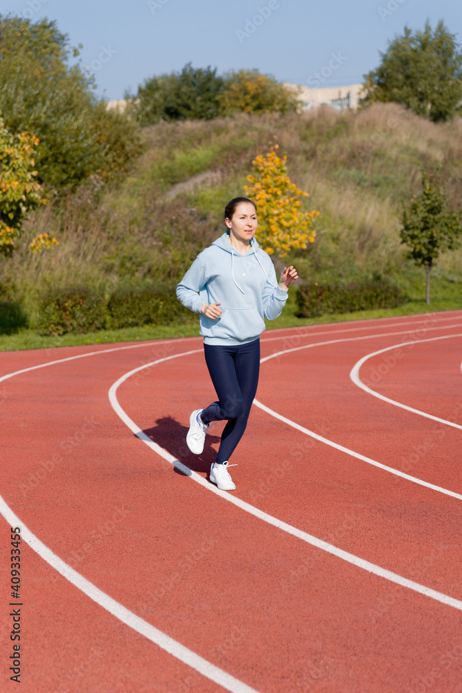 Fototapeta premium Outdoor fitness, public sports field. A young sportswoman does a workout on the street,
