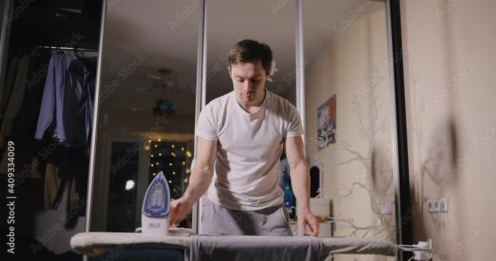 Man ironing clothe at home standing behind the board Man ironing clothe at home standing behind the board