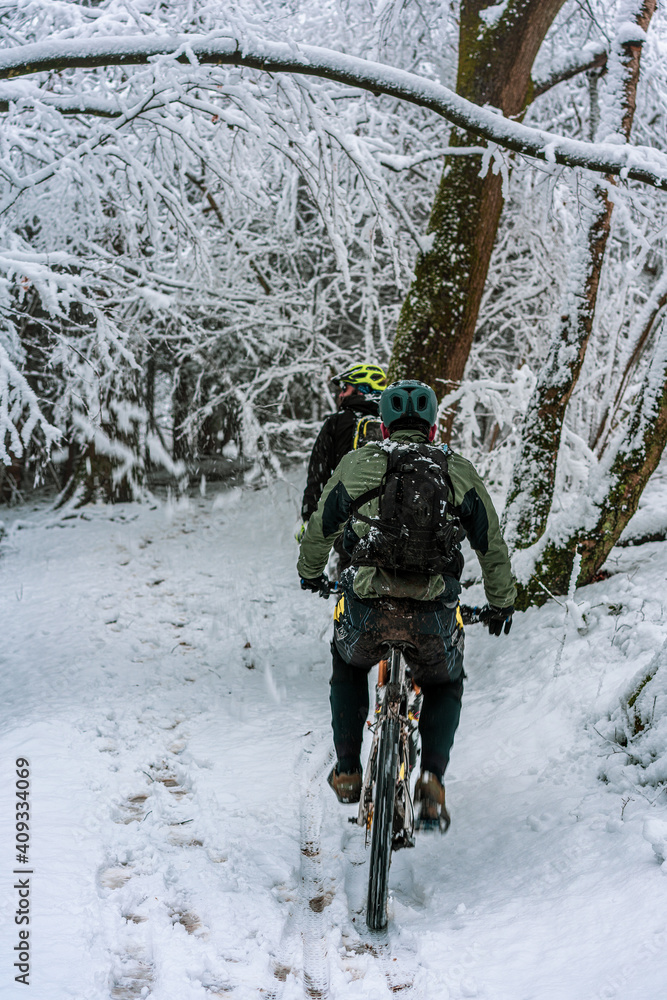 men on mountain bikes in snow-covered forest