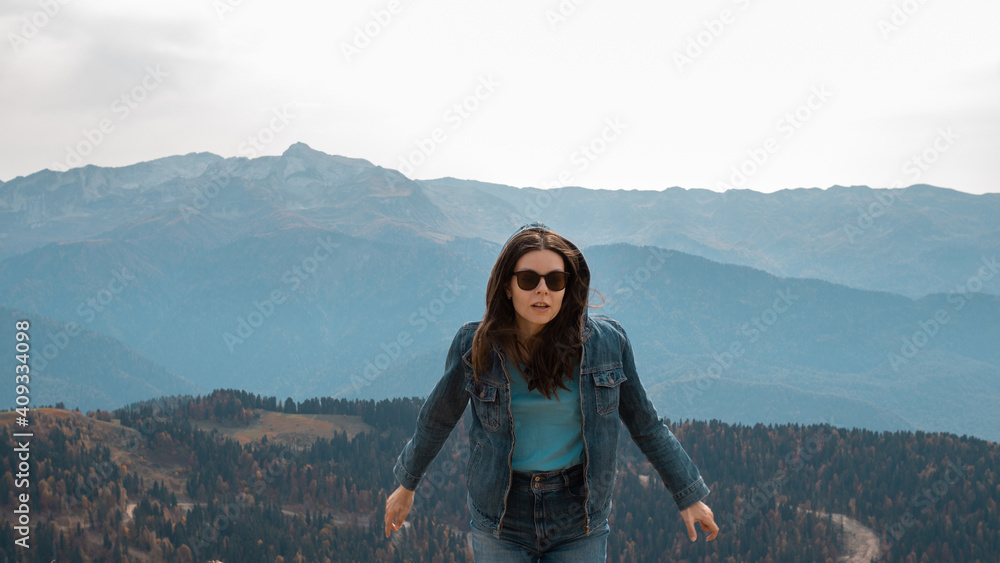 Trekking in the mountains, a young woman jumps and has fun