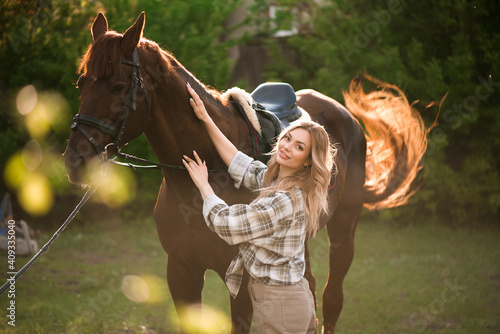 Beautiful girl with her horse and beautiful warm sunset in the spring forest.