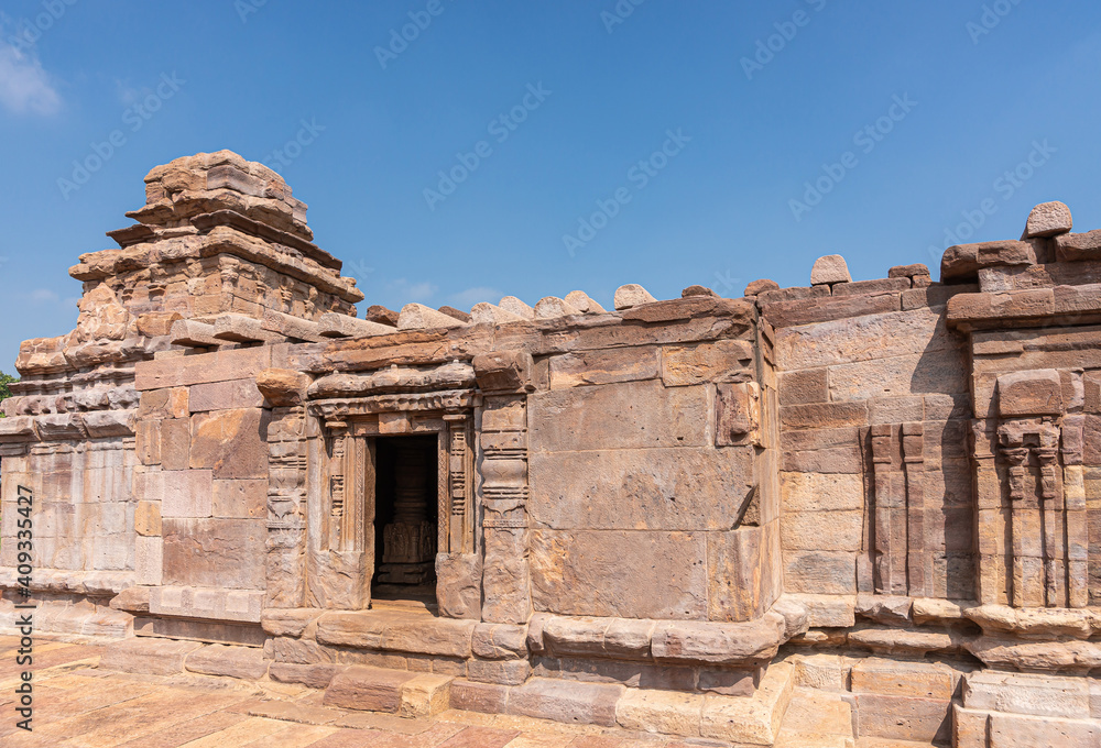 Aihole, Karnataka, India - November 7, 2013: Suryanarayana Temple under blue cloudscape. Heavily damaged brown stone building.