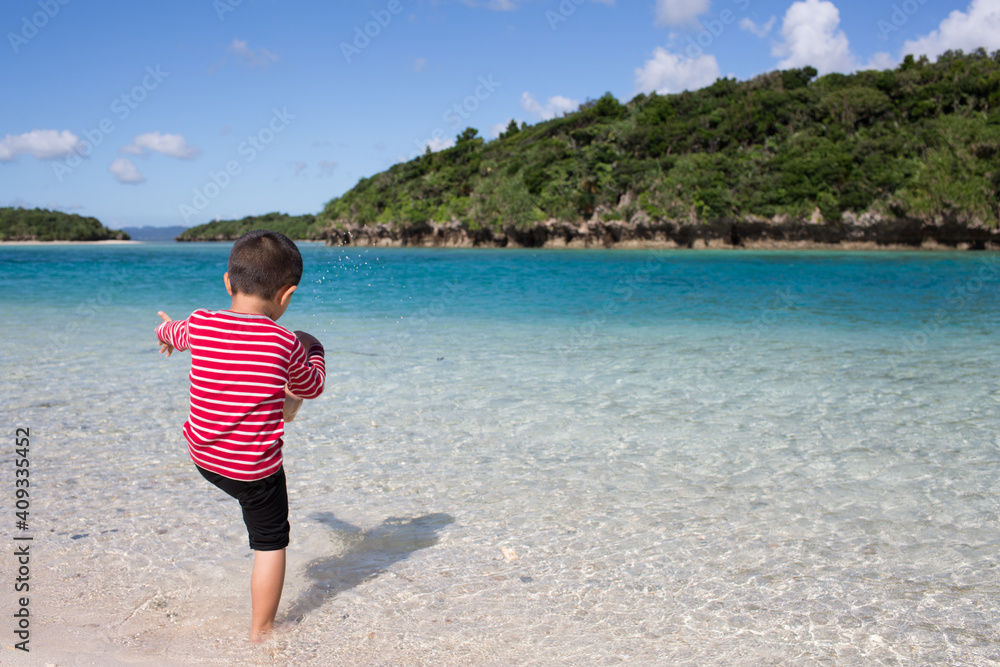 Little boy playing at Kabira Bay on Ishigaki Island, Okinawa, Japan with emerald blue and clear water on a sunny summer day. Little boy playing at Kabira Bay on Ishigaki Island, Okinawa, Japan with emerald blue and clear water on a sunny summer day.