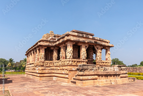 Aihole, Karnataka, India - November 7, 2013: Mandapam side of Brown stone Durga Gudi or Temple under blue sky. Green foliage on sides. Sculptures on pillars.