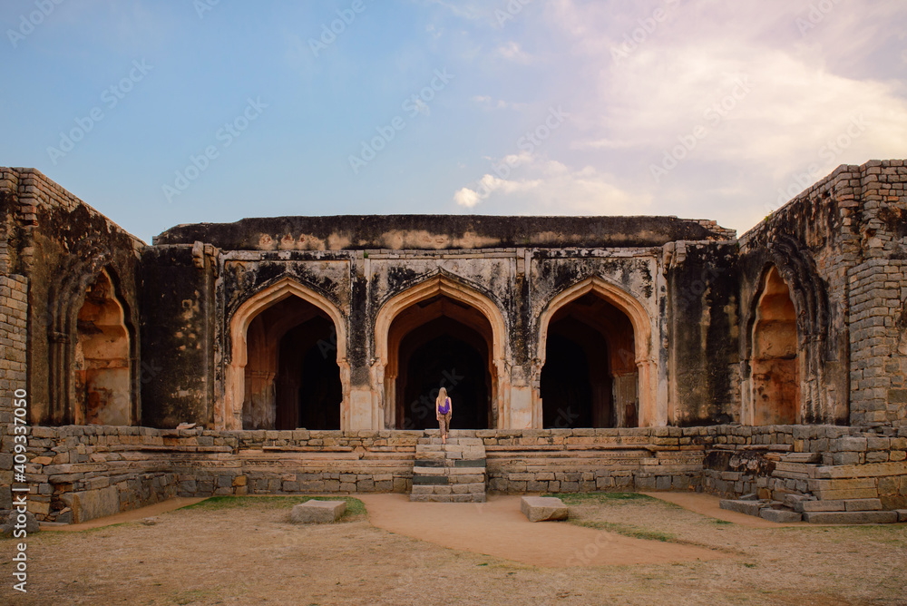 Travel to Hampi city, India, Small figure of woman near ruins Travel to Hampi city, India, Small figure of woman near ruins