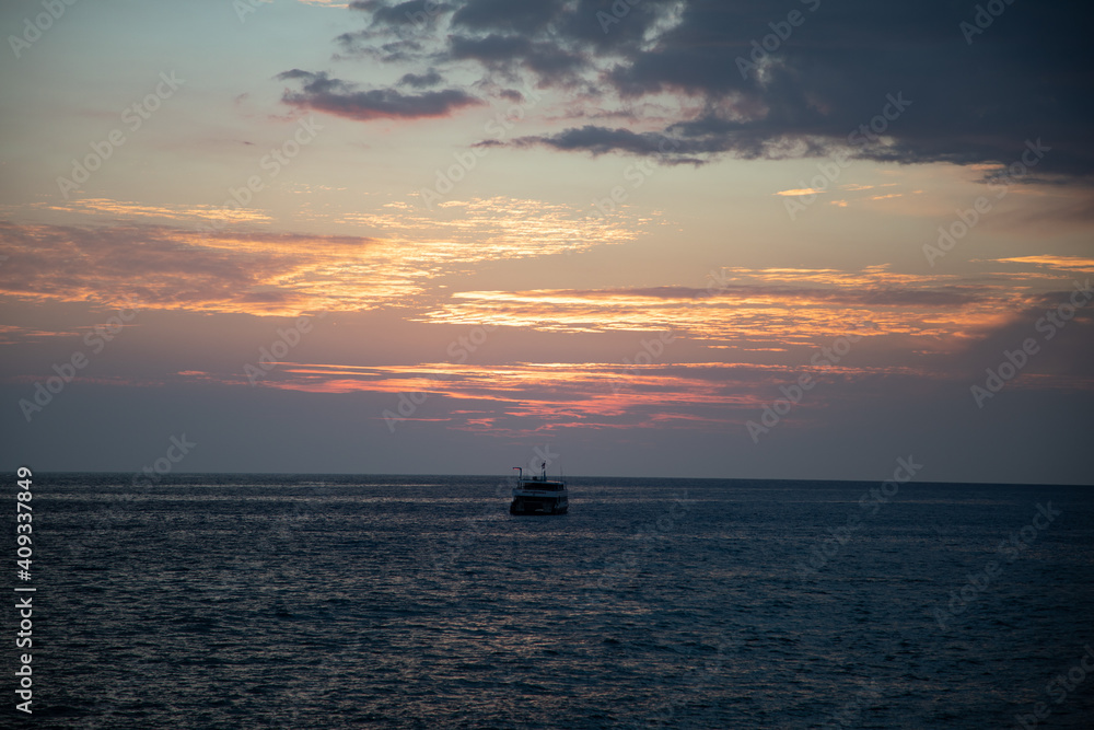 sunset over the sea with a yacht centering the image