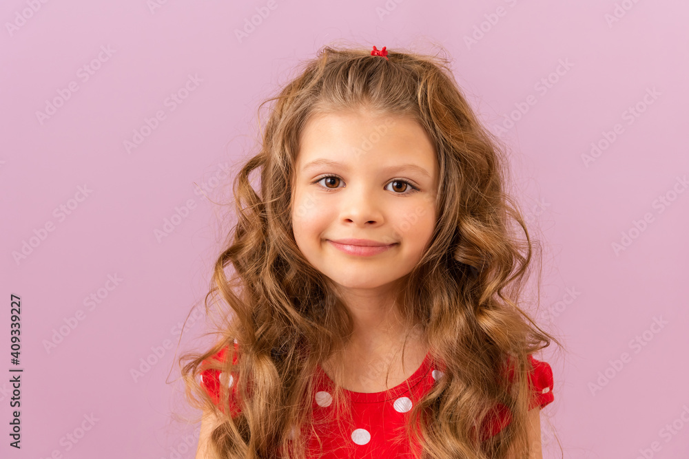 A little girl with curly hair smiles on a purple background. A little girl with curly hair smiles on a purple background.