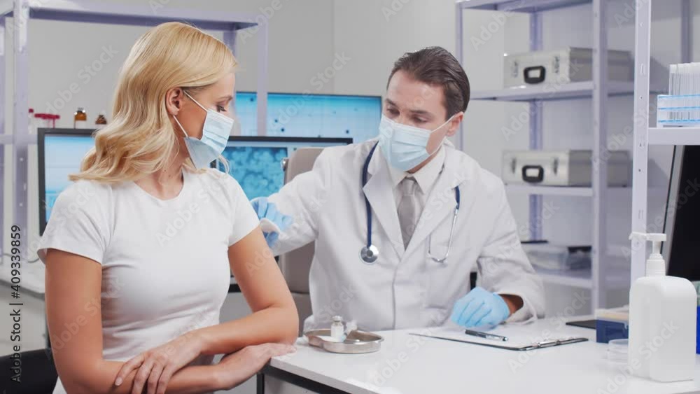 Doctor makes a coronavirus vaccine using a syringe and hypodermic needle. Professional medical worker and patient at the hospital office. Vaccination and safety concept. Doctor makes a coronavirus vaccine using a syringe and hypodermic needle. Professional medical worker and patient at the hospital office. Vaccination and safety concept.