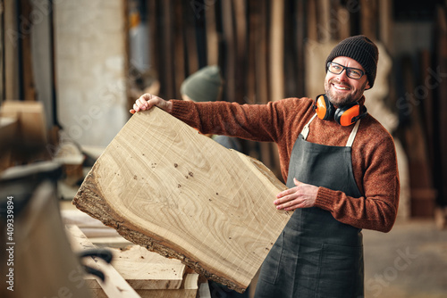 Bild auf Leinwand Happy carpenter with wooden board in workshop